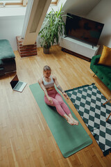 A woman is pumping the press on a yoga mat in living room with laminate flooring