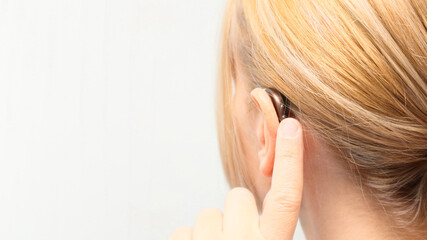 Woman wearing digital hearing aid. Person with disability from the back, medical support, listening and healthcare technology. Deafness treatment, hearing solutions. Place for text.