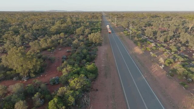 Drone clip showing a 3 carriage truck (road train) driving along straight road, through Australian outback