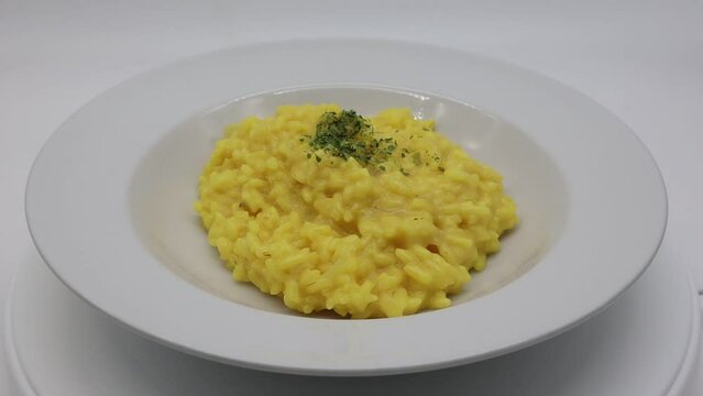 Italian Risotto allo Zafferano (rice with saffron) in a white dish. White background.