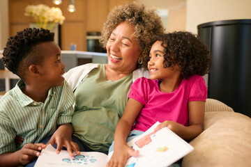 Grandmother Looking After Grandchildren At Home Reading A Story Together