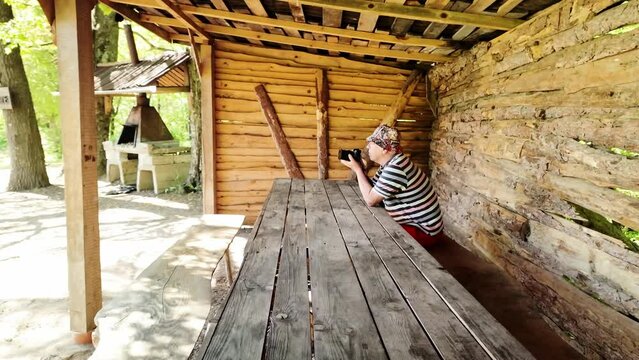 Elderly photographer sat at summer woodland picnic table taking photos