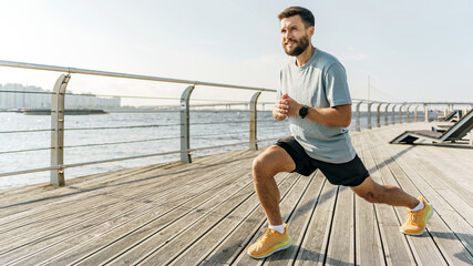 A focused runner performs lunges on a waterfront boardwalk, with a serene river and bridge under a...