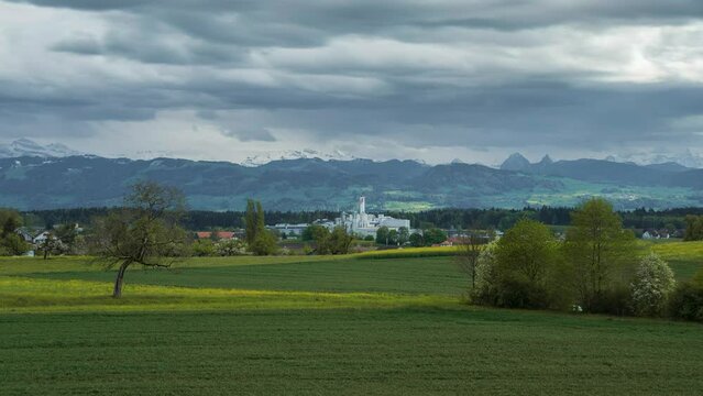The clouds move over Switzerland, Zurich Oberland on a cloudy day. You can see kezo, the combustion site. In the background are snow-capped mountains. Spring