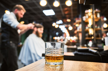 Close-up photo of a glass of whiskey. High-quality barbershop offering drinks to customers. Glass...