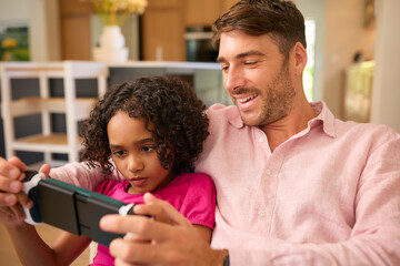 Multi Racial Family With Father And Daughter Playing On Handheld Gaming Device Together - obrazy, fototapety, plakaty
