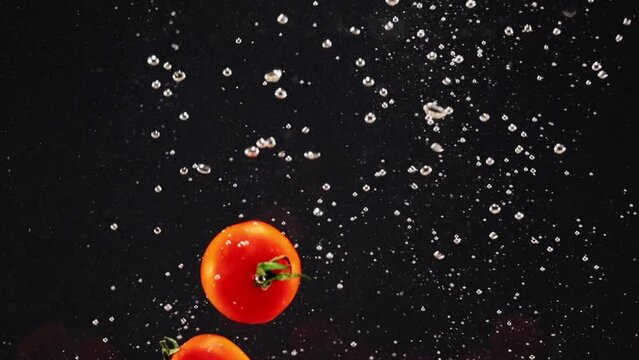 Splash of red tomato with water drops isolated over black background, copy space for advertisement
