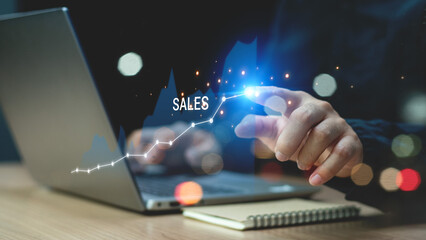 Sale growth concept. Businessman touching graph of increase in sales volume with shopping cart on virtual screen for ecommerce growth. Businessman pointing arrow graph corporate future growth plan