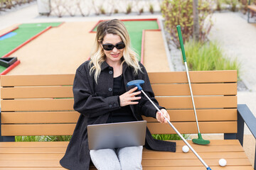 A businesswoman using a laptop on a golf course