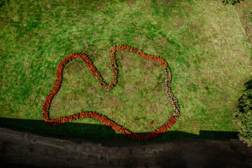 Valmiera, Latvia - August 10, 2023 - Aerial view of a heart-shaped flower arrangement on grass.