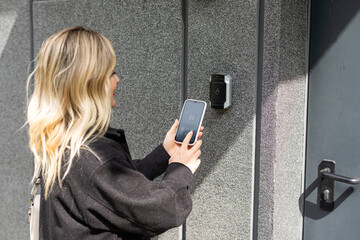 female entering secret key code for getting access and passing building using application on mobile phone, woman pressing buttons on control panel for disarming smart home system - 792757053