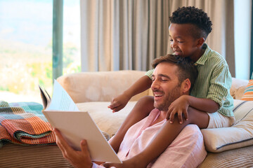 Multi Racial Family At Home With Father And Son Reading Book Together - obrazy, fototapety, plakaty