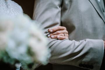 Valmiera, Latvia - August 10, 2023 - Close-up of a groom's hand touching the bride's back, both in...