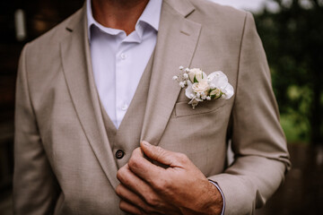 Valmiera, Latvia - August 10, 2023 - A groom adjusting his beige suit jacket with a white...