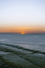 High angle view of cliff by sea against cloudy sky during sunset