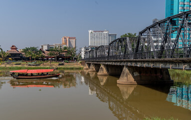 Tourist boat sailing by the Victorian era Iron Bridge in Chiang Mai,Thailand