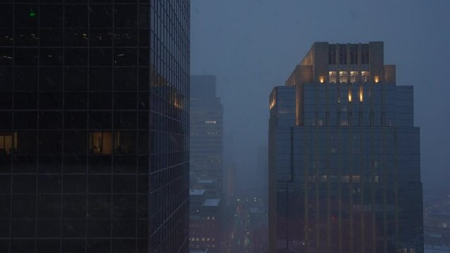 Static establishing shot of tall building in a city during snow storm