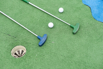  Mini-golf clubs and balls of different colors laid on artificial grass - 792766822