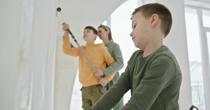 Two young boys actively participate in a home renovation project as they paint the walls of a new apartment. Captures the essence of family involvement and teamwork in DIY home improvement tasks.