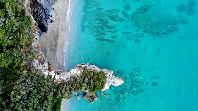 Beach lined with rocks and crystal clear water glows in beautiful turquoise colors.