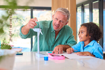 Family With Grandfather And Granddaughter Doing Homework On Green Energy With Model Turbine