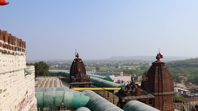 ancient hindu temple with waving holy flag and misty city background from at morning video is taken at Osiyan sacchiyay Mata Temple, jodhpur, rajasthan, India.