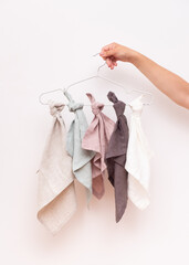 The female hand holds a hanger with scarves made of linen fabric