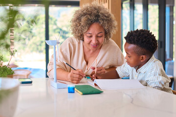 Multi Racial Family With Grandmother And Grandson Doing Homework On Green Energy With Model Turbine