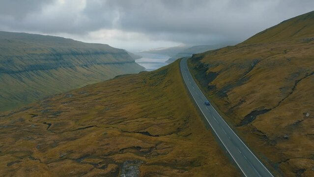 Scenic Drive: Aerial Cinematography of Car Moving Through Spectacular Faroe Islands Landscape with Drone.