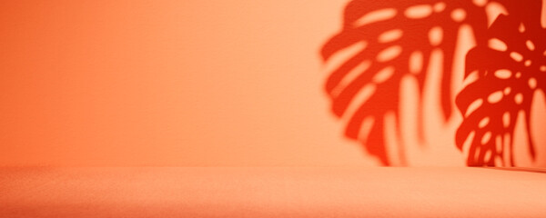 Tropical summer background with monstera palm leaf shadow on orange wall. Empty room for luxury brand product placement mockup.