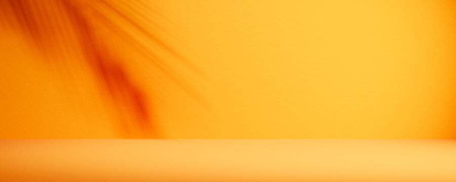 Tropical summer background with palm shadow on yellow wall. Empty orange room for luxury brand product placement mockup.