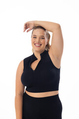 Smiling Caucasian plus-size model poses, hand on head, against white background
