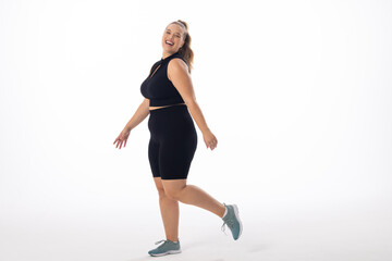 Caucasian young female plus size model on white background is laughing and walking, copy space - 792789484