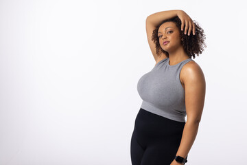 Biracial young female plus size model on white background, hand on head, copy space