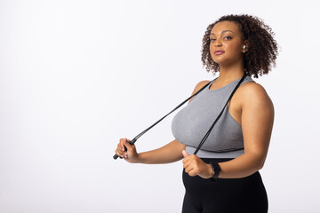 A biracial young female plus size model holds resistance bands on white background, copy space - 792789625