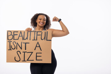 Biracial plus-size young woman flexes arm with a poster on white background, copy space