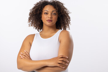 Biracial young plus size model stands with arms crossed on white background, copy space
