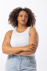 Biracial plus size model stands with arms crossed on white background