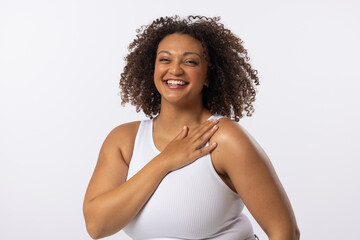A biracial plus size model with curly brown hair laughs on white background, copy space - Powered by Adobe