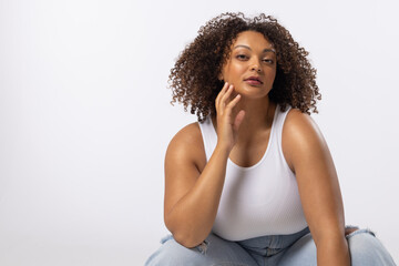A biracial young female plus size model sits on white background, copy space - 792789839