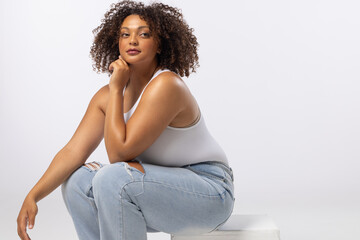 Biracial plus size model sits on white background, copy space - 792789844