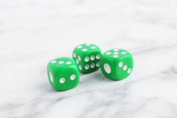 Three green game dices on white marble table, closeup