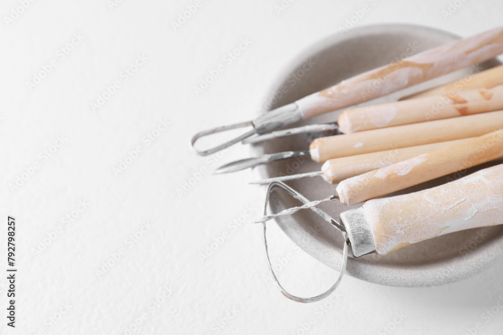 Wall mural Set of different clay crafting tools on white table, closeup. Space for text