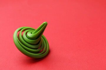 One green spinning top on red background, space for text