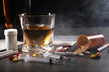 Alcohol and drug addiction. Whiskey in glass, syringes, pills and cigarettes on grey table - obrazy, fototapety, plakaty