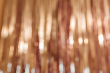 Yellow foil strip background. Blurred with bokeh. Curtain hanging on wall. Festive, Christmas, New Year or anniversary party concept. Decorative wallpaper