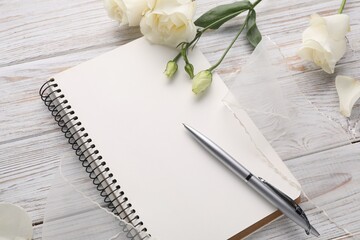 Guest list. Notebook, pen, rose flowers and ribbon on wooden background, above view