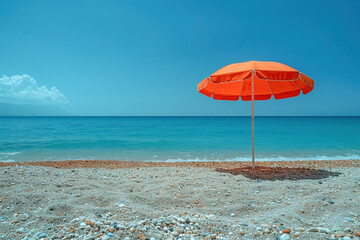 Sonnenschirm am menschenleeren Strand vor blauem Meer und Himmel