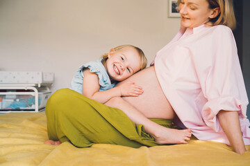 Pregnant mother and daughter together at home. Woman with her first child during second pregnancy. Motherhood and parenting concept. Toddler smiling girl and mom. Happy family expecting for new baby. - 792807265