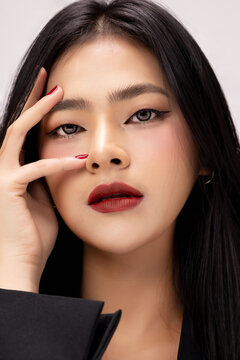 Young sexy fashionable Asian woman wearing black jacket shows perfect red lips in studio. Cosmetics, femininity.